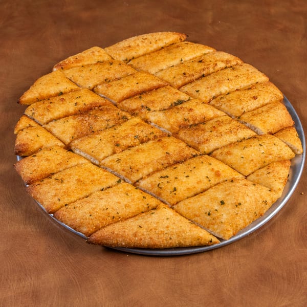 Mark & Monica's Family Pizza's golden-brown garlic breadsticks, cut into diamond shapes, on a metal pizza pan.